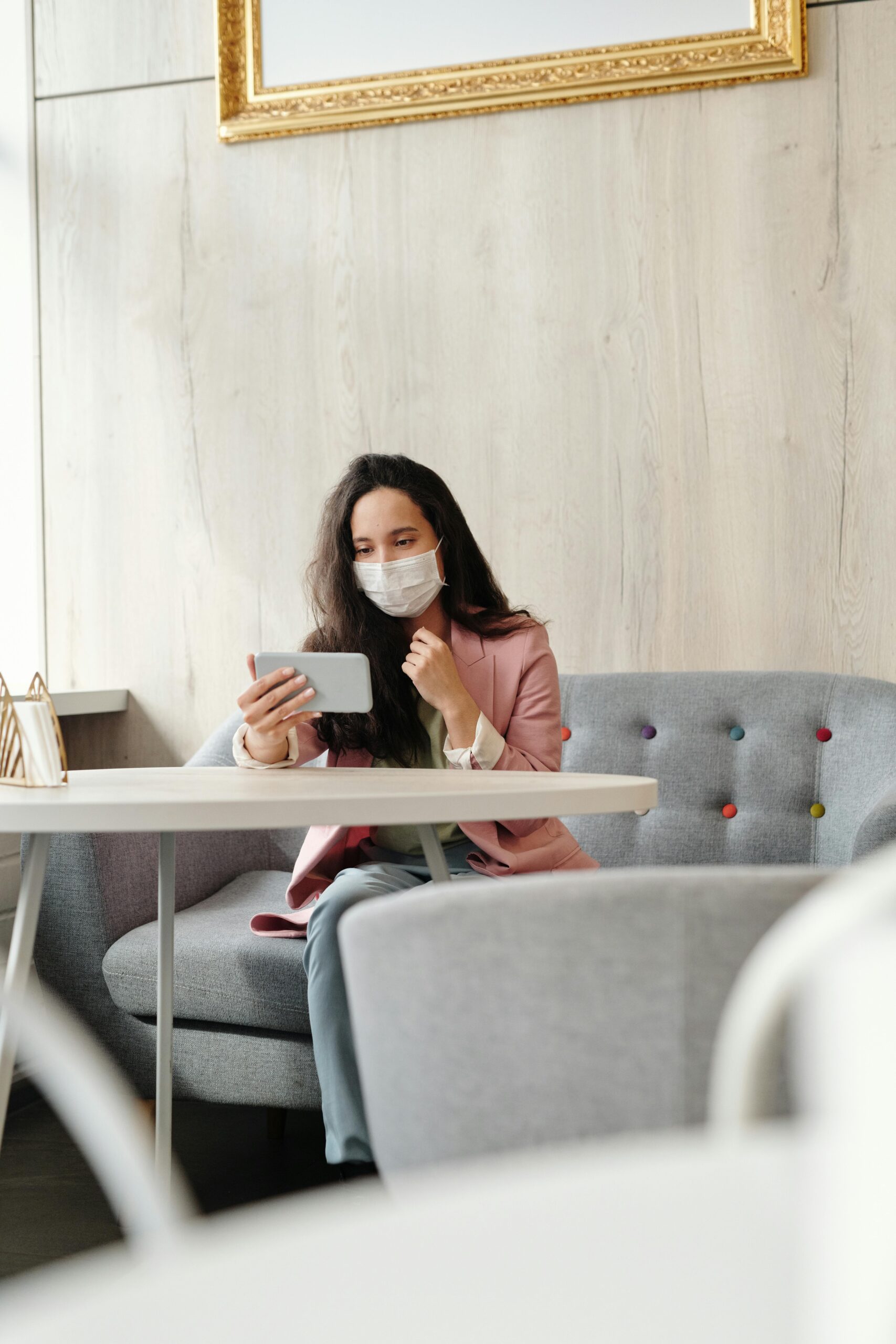 Woman wearing a mask, using her phone in a cafe.
