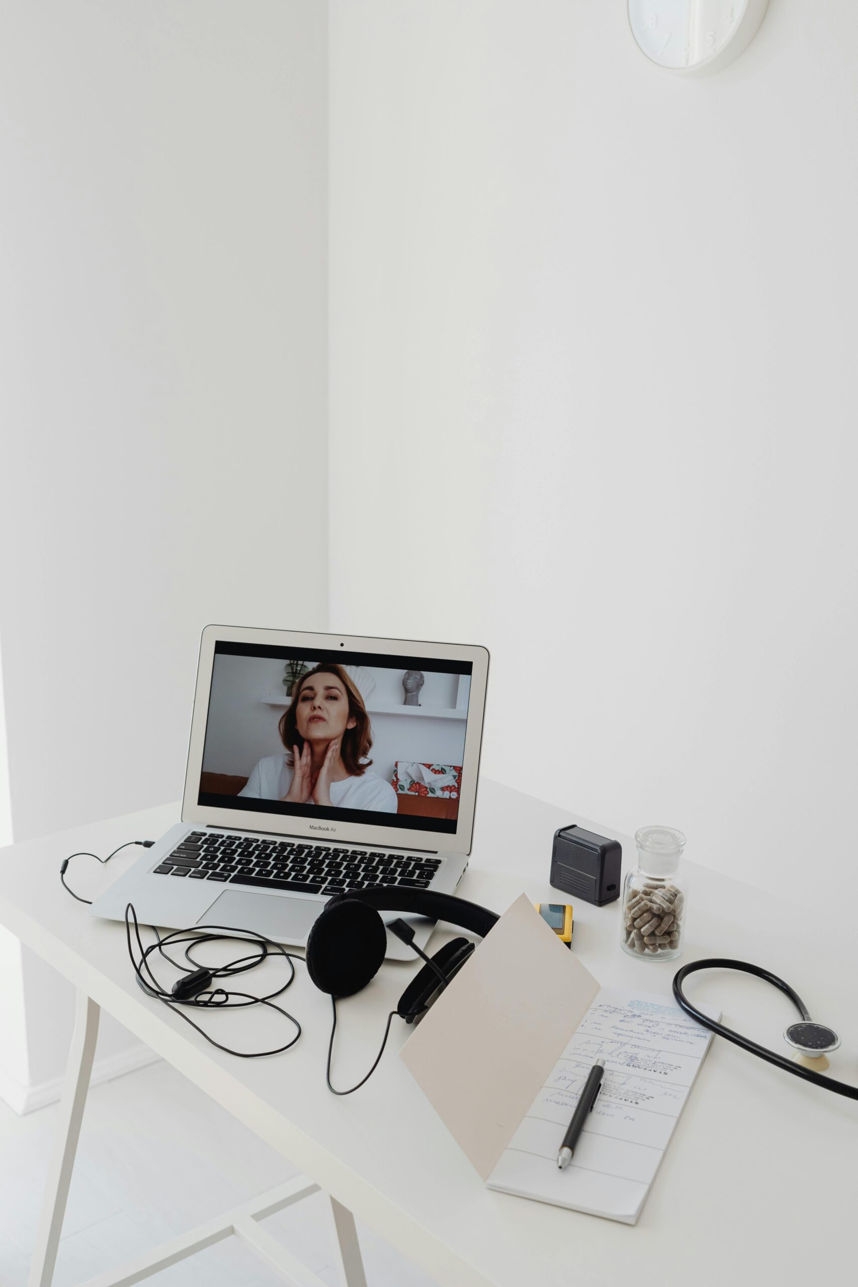 A laptop on a desk with headphones and a video call on screen.