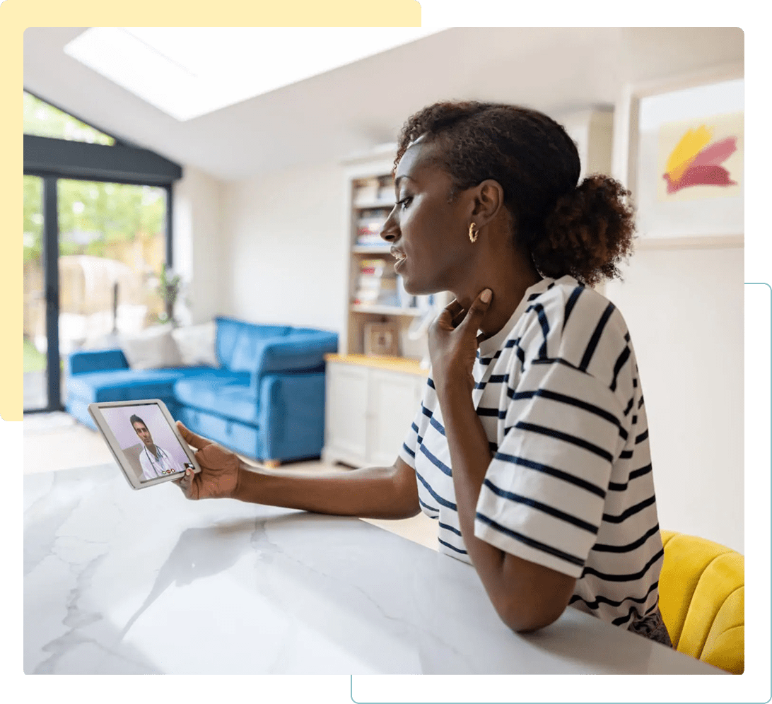 Woman reading on a tablet while sitting on a bed in a cozy room.