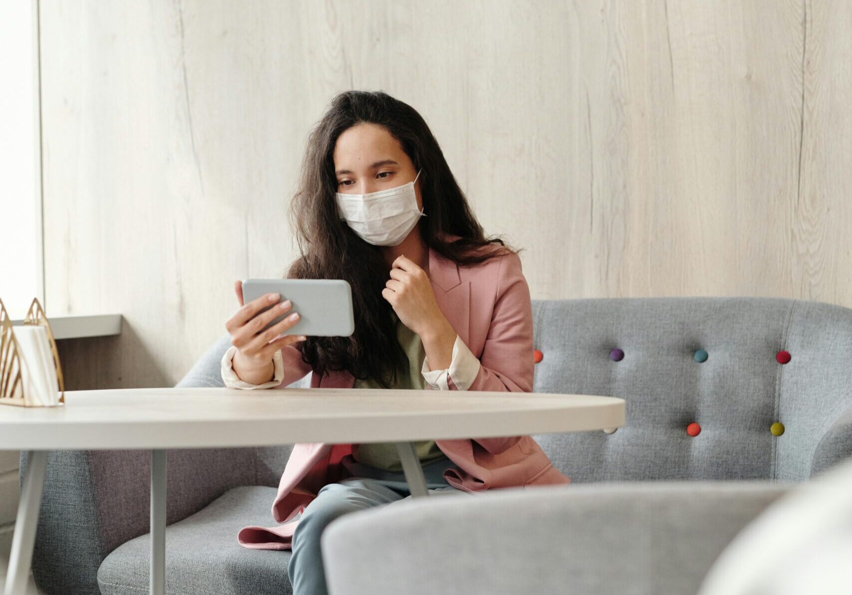 Woman wearing a mask, using her phone in a cafe.