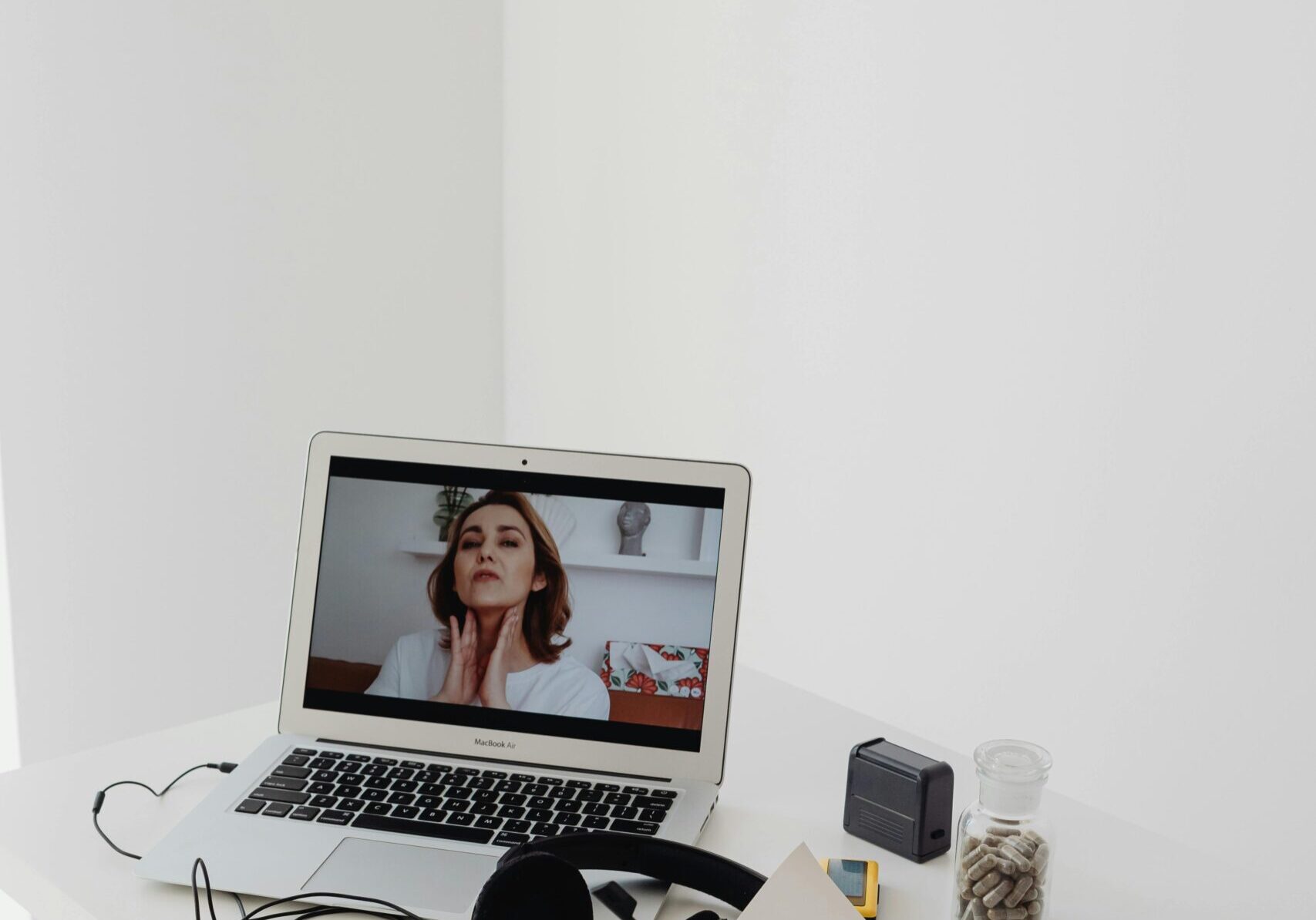 A laptop on a desk with headphones and a video call on screen.